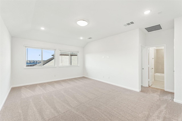 unfurnished room featuring light carpet and vaulted ceiling