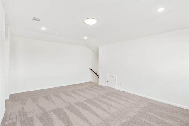 carpeted spare room featuring vaulted ceiling