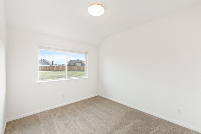 carpeted spare room featuring vaulted ceiling