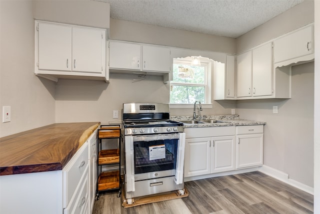 kitchen featuring white cabinets, gas range, light wood-type flooring, and sink