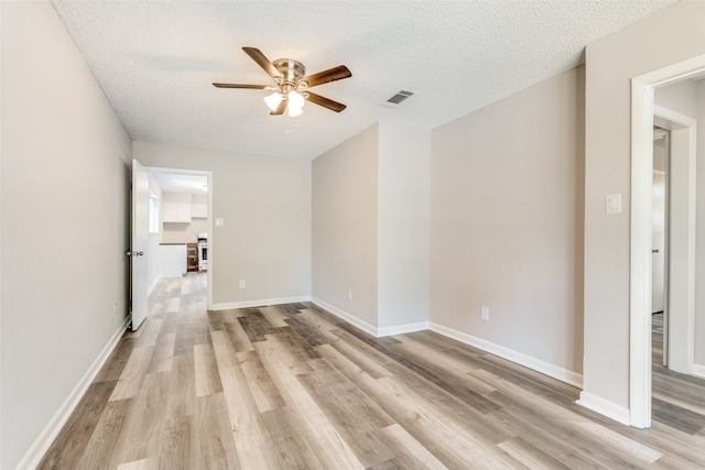 empty room with ceiling fan, a textured ceiling, and light hardwood / wood-style floors