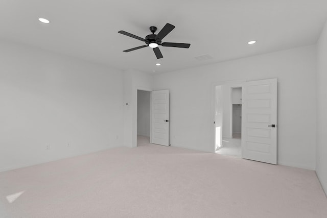 unfurnished bedroom featuring a spacious closet, light colored carpet, and ceiling fan