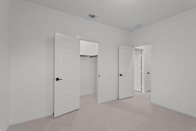 unfurnished bedroom featuring a spacious closet, light carpet, and a closet