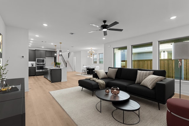 living room featuring sink, ceiling fan with notable chandelier, and light wood-type flooring