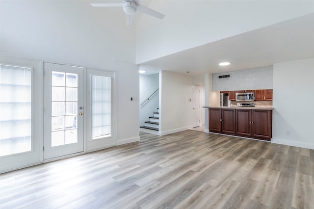 unfurnished living room with a healthy amount of sunlight, ceiling fan, and light hardwood / wood-style flooring