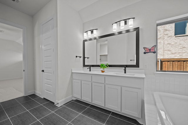 bathroom featuring tiled tub, vanity, lofted ceiling, and tile patterned floors