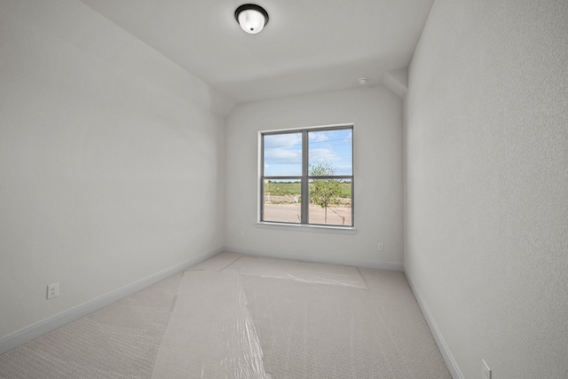 unfurnished room featuring vaulted ceiling and light colored carpet