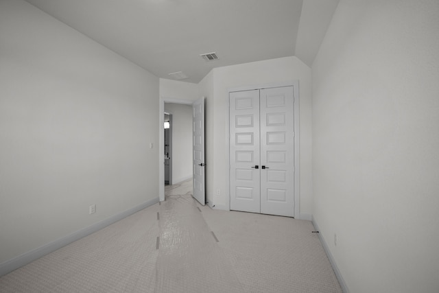 unfurnished bedroom featuring light carpet and a closet