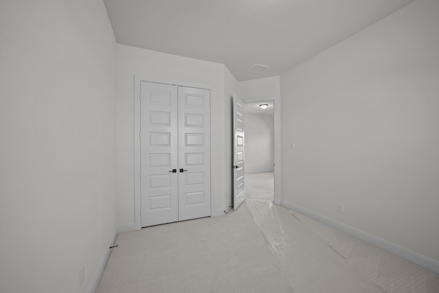 unfurnished bedroom featuring a closet and light colored carpet