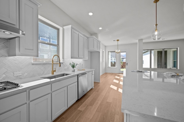 kitchen with pendant lighting, stainless steel appliances, sink, and a wealth of natural light