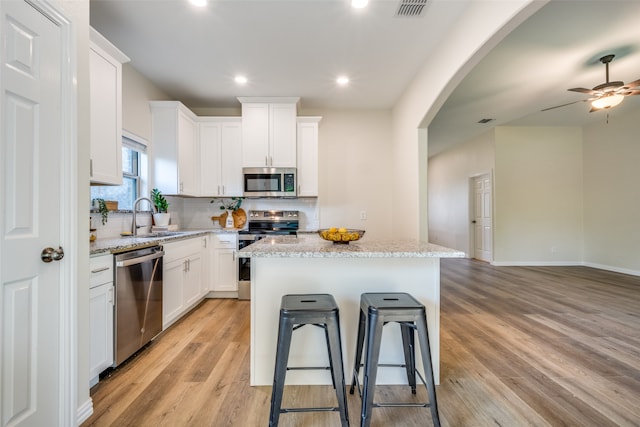 kitchen with a center island, stainless steel appliances, white cabinets, and light hardwood / wood-style floors