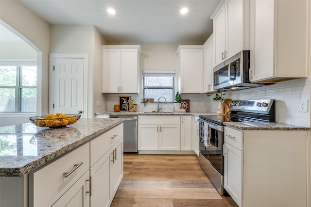 kitchen with appliances with stainless steel finishes, a healthy amount of sunlight, light hardwood / wood-style flooring, and sink