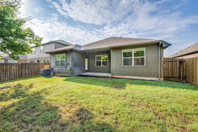 rear view of property with central air condition unit and a yard