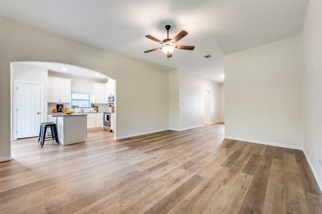 unfurnished living room featuring ceiling fan, sink, and light wood-type flooring