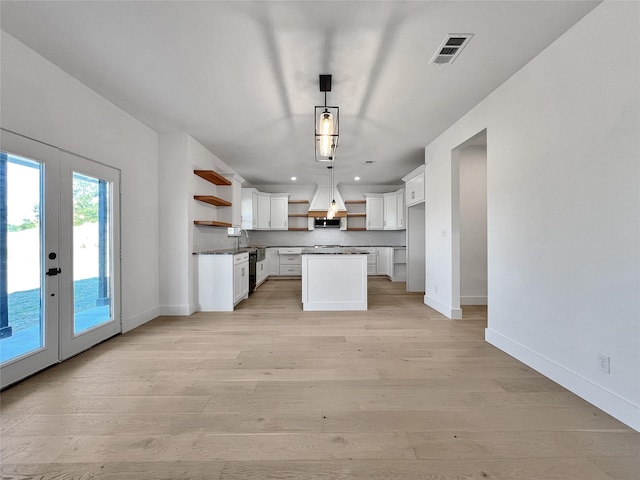 kitchen featuring a kitchen island, pendant lighting, white cabinets, and light wood-type flooring