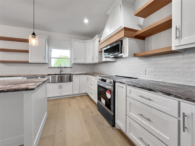 kitchen featuring appliances with stainless steel finishes, decorative light fixtures, white cabinetry, sink, and light wood-type flooring