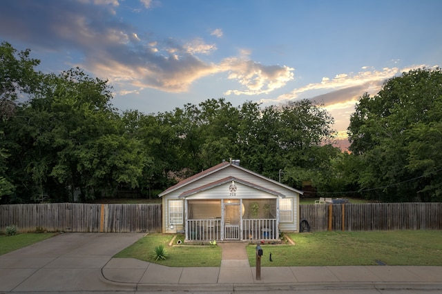 bungalow-style home featuring a porch, a front lawn, and fence