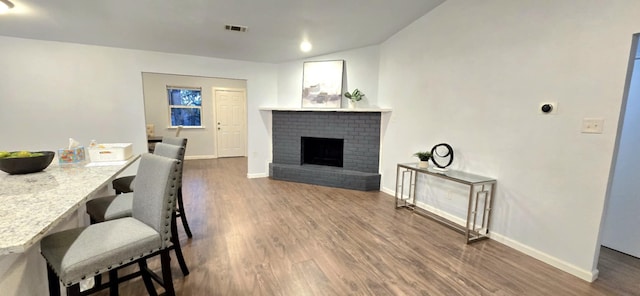 dining area featuring a brick fireplace and dark hardwood / wood-style floors