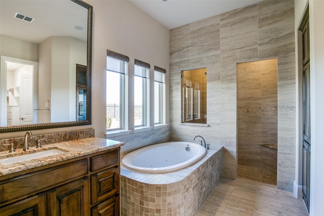 bathroom featuring tile patterned flooring, vanity, tile walls, and plus walk in shower