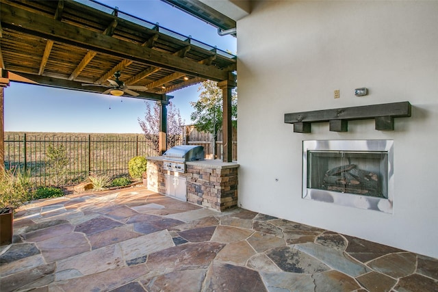 view of patio / terrace with exterior kitchen, ceiling fan, a grill, and exterior fireplace