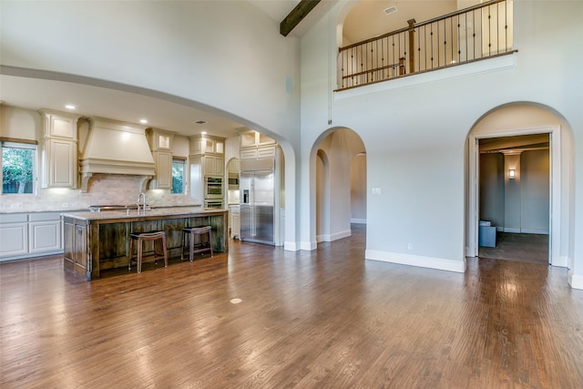 interior space featuring a towering ceiling, dark wood-type flooring, and beam ceiling