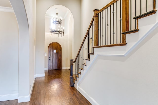 foyer entrance featuring a high ceiling, ornamental molding, a chandelier, and dark hardwood / wood-style flooring