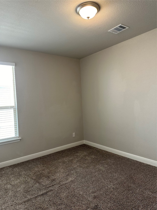 spare room with a textured ceiling and carpet floors