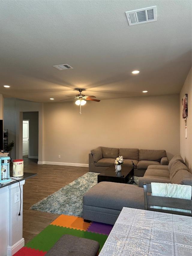 living room featuring ceiling fan, dark hardwood / wood-style floors, and a textured ceiling