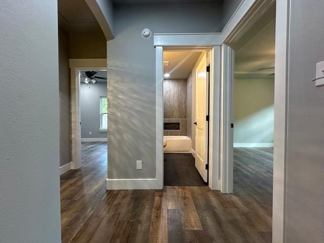 corridor featuring arched walkways, baseboards, and wood finished floors