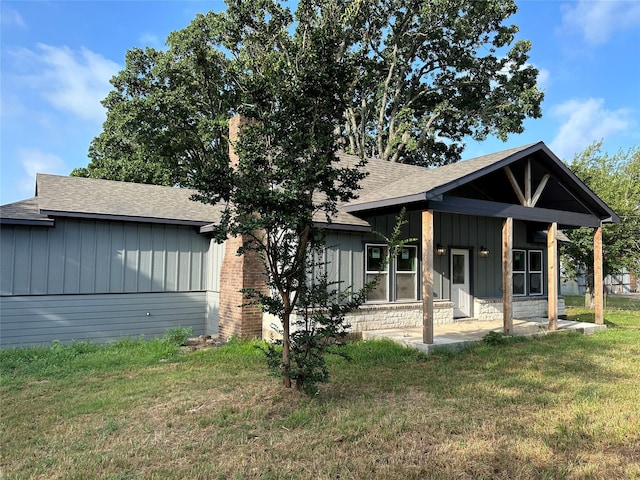 view of front of house with board and batten siding, a shingled roof, and a front lawn