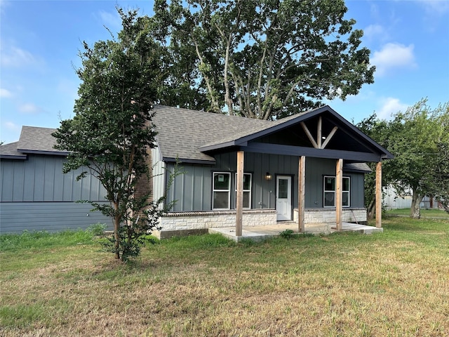 view of front of home with a shingled roof, a front lawn, and board and batten siding