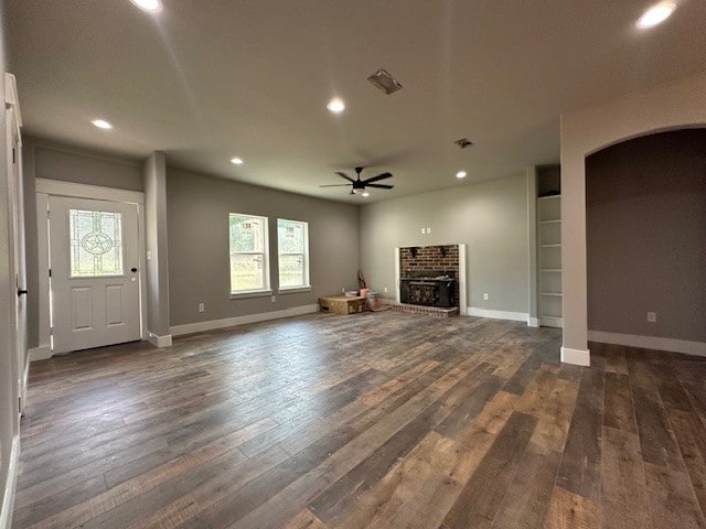 unfurnished living room featuring dark wood-type flooring, ceiling fan, and a fireplace