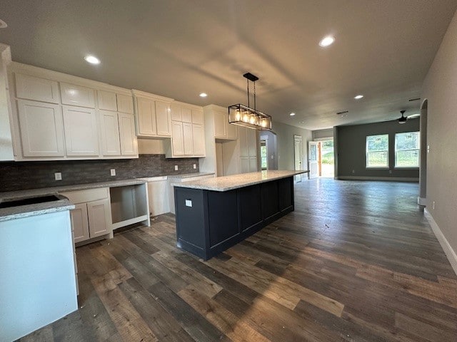 kitchen with dark wood-type flooring, ceiling fan, a center island, and white cabinetry