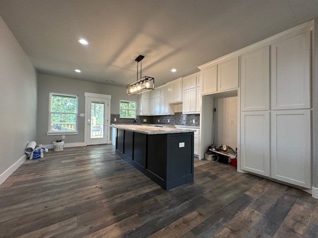 kitchen with a kitchen island, dark hardwood / wood-style flooring, pendant lighting, backsplash, and white cabinetry