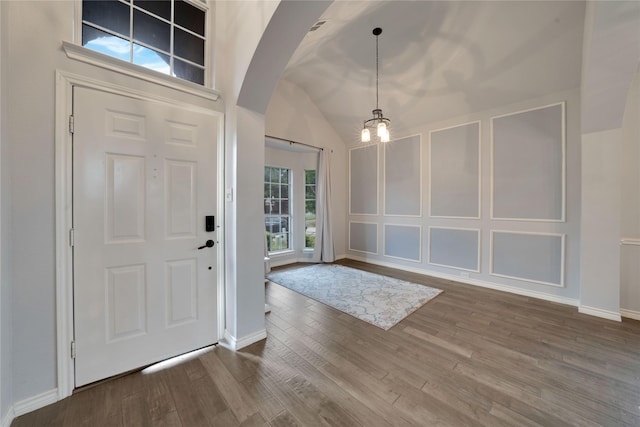 entryway featuring vaulted ceiling, hardwood / wood-style flooring, and an inviting chandelier