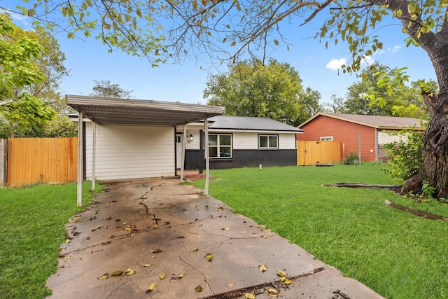 view of front of house featuring brick siding, concrete driveway, fence, an attached carport, and a front lawn