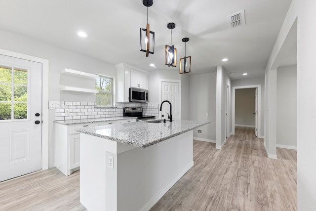 kitchen with a center island with sink, light hardwood / wood-style flooring, appliances with stainless steel finishes, and white cabinetry