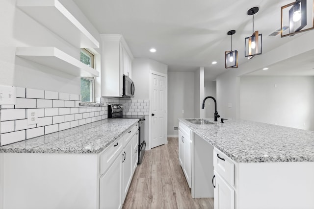 kitchen featuring a kitchen island with sink, pendant lighting, white cabinetry, stainless steel appliances, and sink