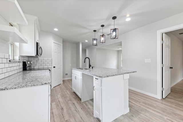 kitchen featuring white cabinetry, an island with sink, sink, and light hardwood / wood-style floors