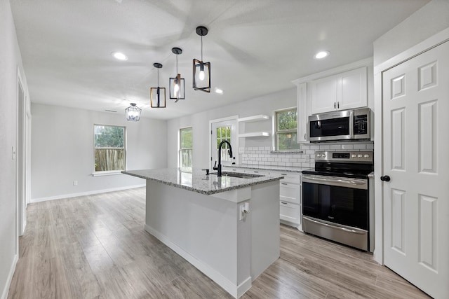 kitchen featuring an island with sink, a healthy amount of sunlight, stainless steel appliances, and white cabinets