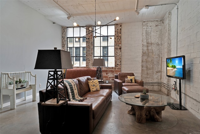 living room featuring concrete flooring, brick wall, and rail lighting