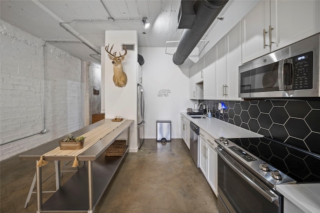 kitchen featuring brick wall, sink, white cabinets, backsplash, and stainless steel appliances