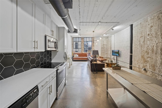 kitchen featuring concrete flooring, white cabinetry, appliances with stainless steel finishes, brick wall, and backsplash