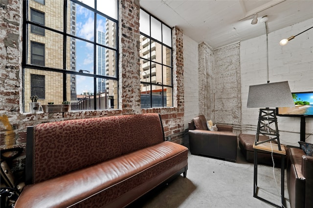 living area with concrete flooring and brick wall