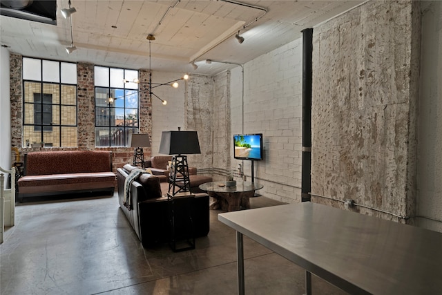 living room with a notable chandelier, concrete floors, and brick wall