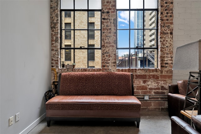 sitting room featuring brick wall, a healthy amount of sunlight, and concrete floors