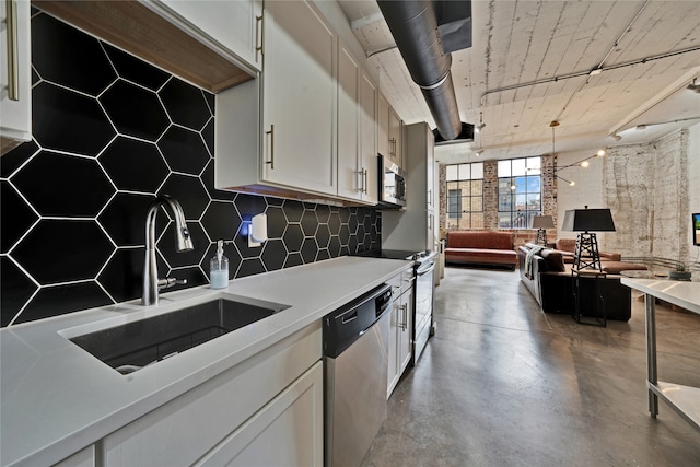 kitchen featuring decorative light fixtures, sink, concrete floors, white cabinets, and stainless steel appliances