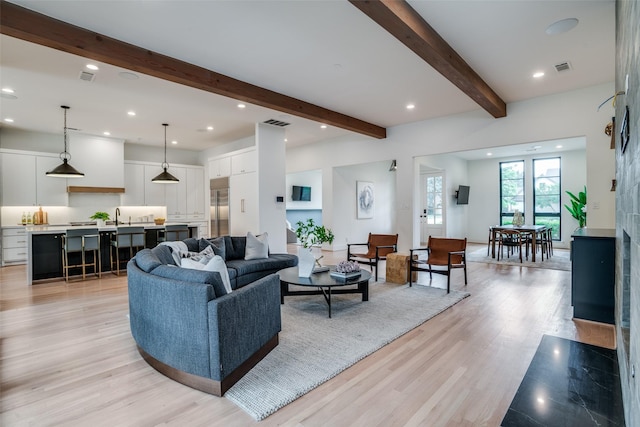 living room featuring light hardwood / wood-style floors, sink, and beamed ceiling