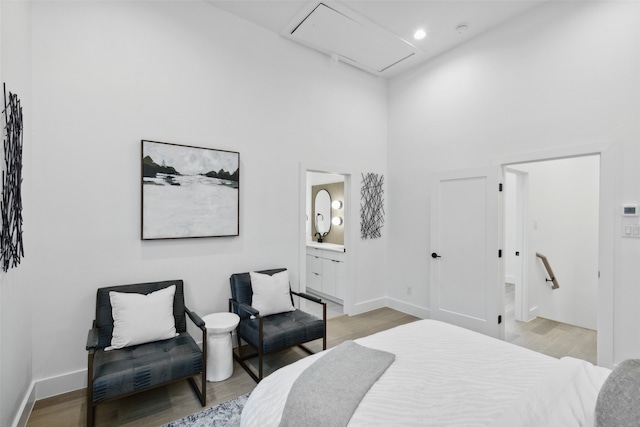 bedroom with a high ceiling, light wood-type flooring, and ensuite bathroom