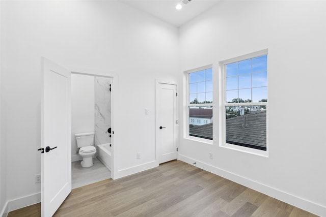 unfurnished bedroom featuring ensuite bath and light wood-type flooring